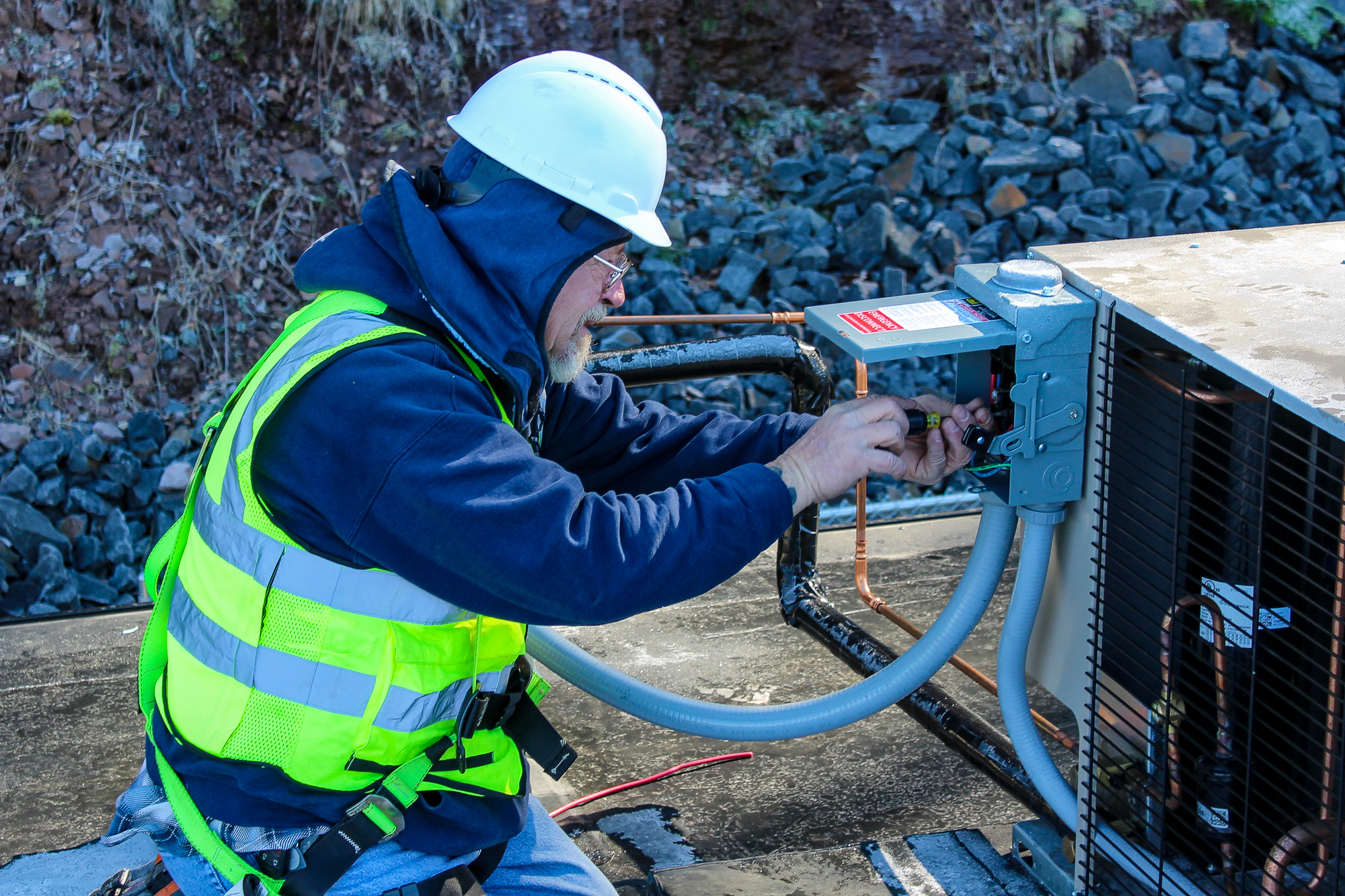 Electrician dressed for cold weather installing an outdoor generator, showcasing professional electrical craftsmanship and all-weather readiness.