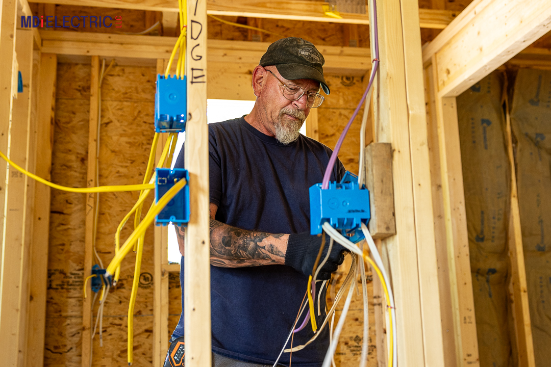 Experienced MDI Electrical worker installing a wiring box in the framework of a home before the finishing work, demonstrating expert electrical craftsmanship and construction safety.